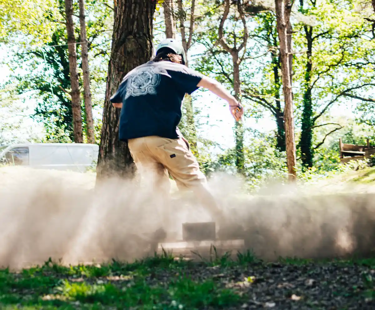 Rider Evo-Spirit en accélération projetant un nuage de poussière dans une clairière, vu de dos
